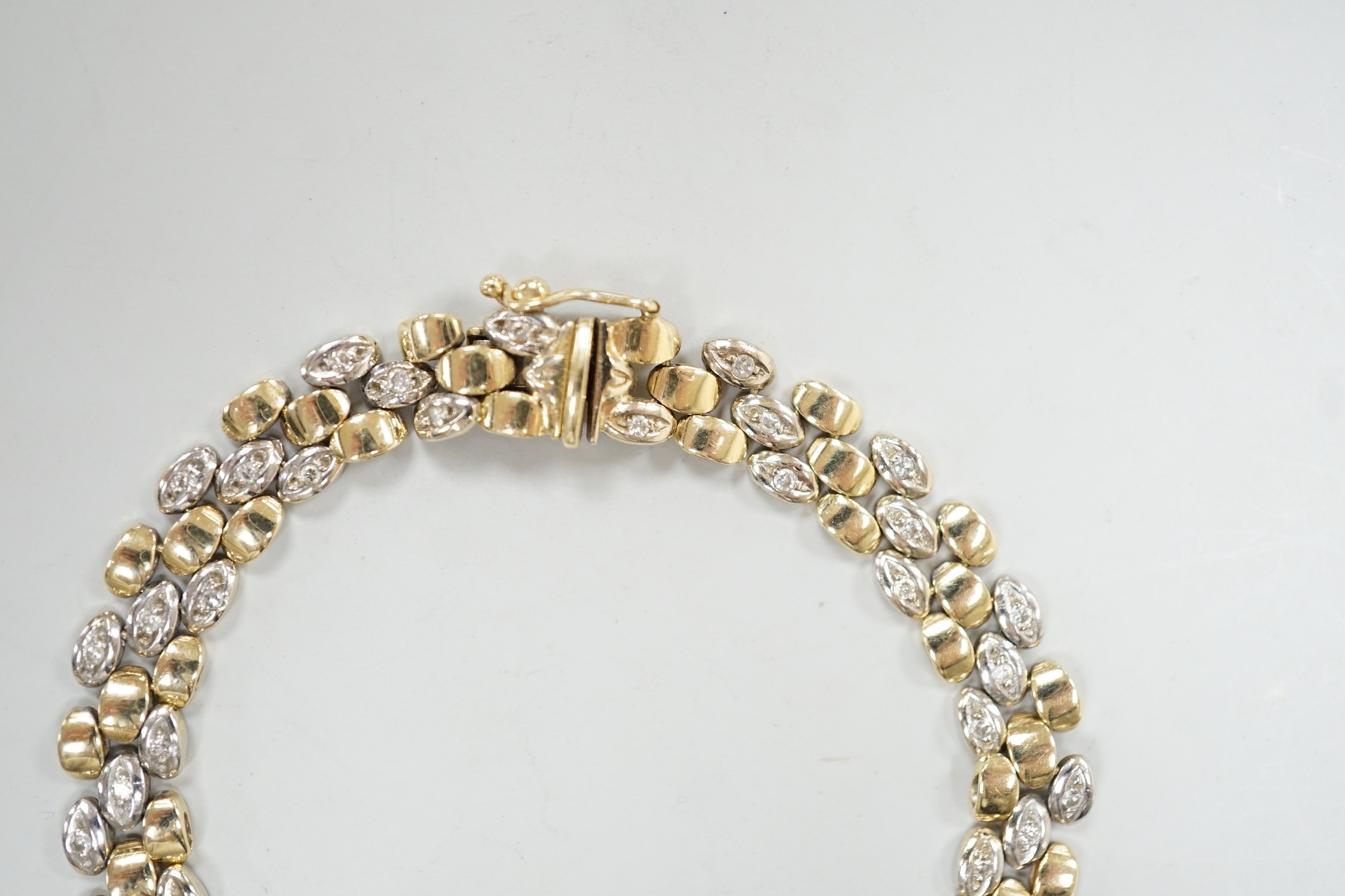 A modern two colour 585 and diamond chip set bracelet, 18cm, gross weight 17.3 grams.